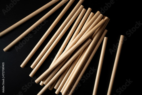 Stacks of wooden dowels arranged on a black surface in an artistic display for crafting or construction projects
