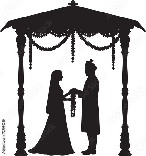 Indian wedding couple exchanging garlands under a canopy