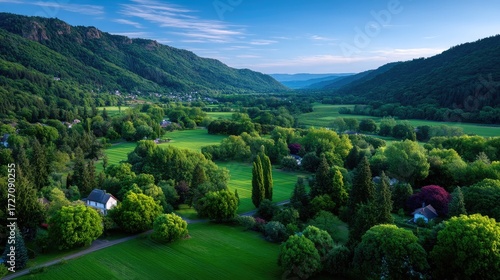 Lush Green Valley Aerial View with Rolling Hills and Forested Landscape Under Bright Blue Sky in Cinematic HDR Lighting Style