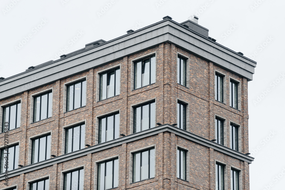 Fototapeta premium modern multi-storey apartment building, brown brick building with glass windows, urban background