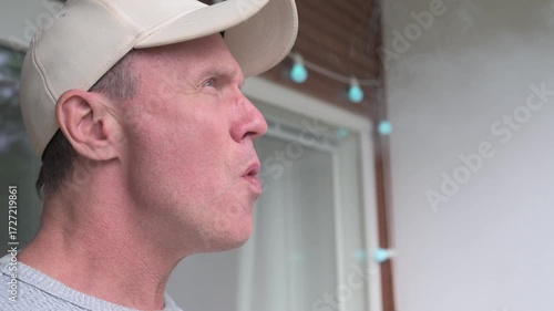 Mature man smoking mini cigar outdoors in balcony close-up