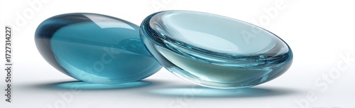 Two smooth, translucent teal ovals rest on a white surface, their curved forms creating subtle highlights and shadows