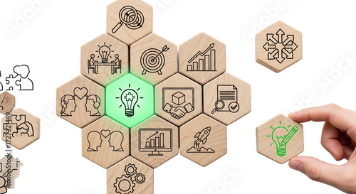 Hand placing glowing green idea lightbulb block into wooden hexagon business strategy puzzle. Innovation and growth concept.
