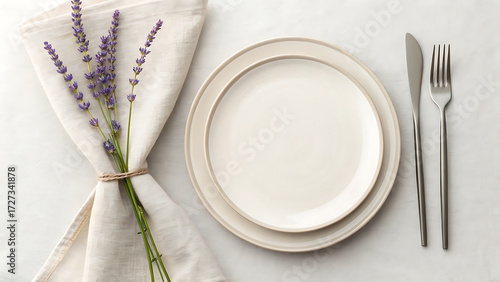 Elegant table setting with oval plates silverware and a sprig of dried lavender tied with a napkin