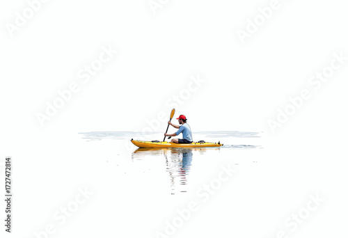 Solitary kayaker paddling across serene lake surrounded by tranquil water and vast open sky on a peaceful and reflective outdoor adventure excursion