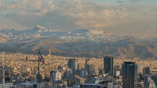 Wallpaper Mural Daylight view of Tehran city with the Iranian flag in the foreground and the snow-covered Alborz mountains in the background, blending urban skyline with majestic nature. Torontodigital.ca