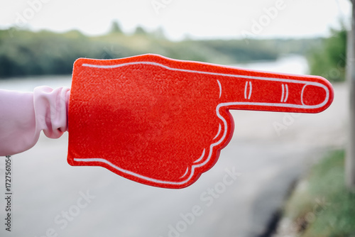 young woman hand with large red rubber glove with pointing finger, pointing right, volunteer work, setting direction
