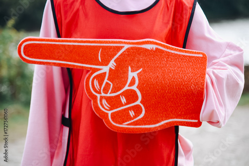 young woman hand with large red rubber glove with pointing finger, pointing left, volunteer work, setting direction