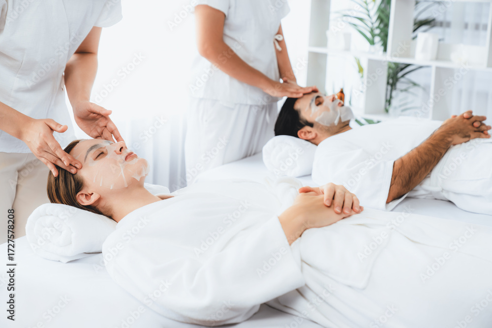 Obraz premium Serene modern daylight ambiance of spa salon, couple customer indulges in rejuvenating with facial skincare mask. Facial skin treatment and beauty cosmetology procedure for face. Quiescent