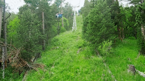 Handheld real-time POV footage of person riding ski lift in summertime. FPV from chair ski lift footage