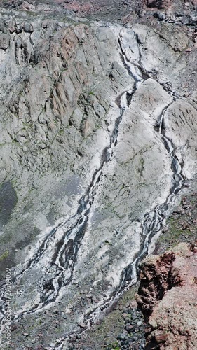 Mountain stream flows along the steep cliffs dividing into many small streams. Headwaters of mountain river in highland