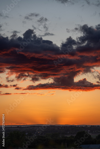 Slika na platnu Unusual shaped clouds with a red tinge and an orange sky.
