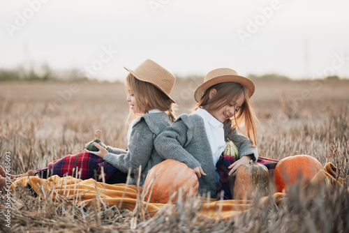 Twin girls enjoying a peaceful afternoon in a pumpkin patch during autumn season