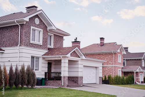 Tableau sur toile Modern Suburban Brick Houses With Driveways and Well-Maintained Lawns Under Clou
