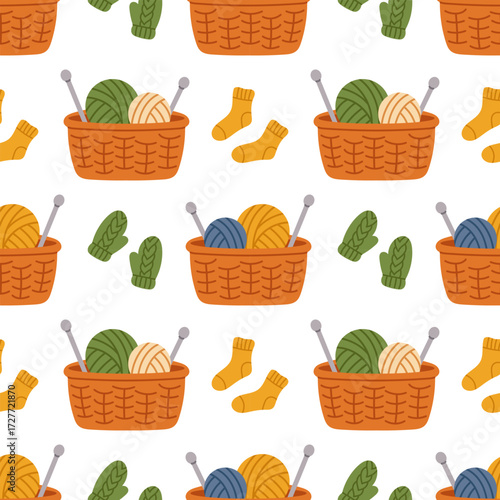 Vector seamless pattern with cozy knitted woolen socks and mittens, and baskets of wool yarn balls. Cozy knitting tools on white background. Seamless pattern in flat design.