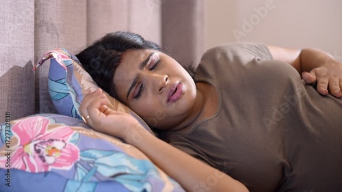 An expecting woman lying in bed - stomach ache  unpleasant pregnancy  tough pregnancy  unhealthy  nursing care. A young to-be mother holding her tummy while sleeping - feeling uncomfortable  unborn...
