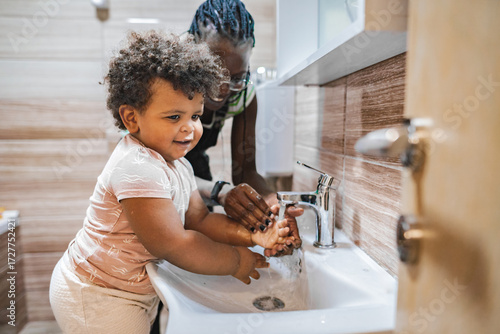 Joyful child learns handwashing in a cozy bathroom setting