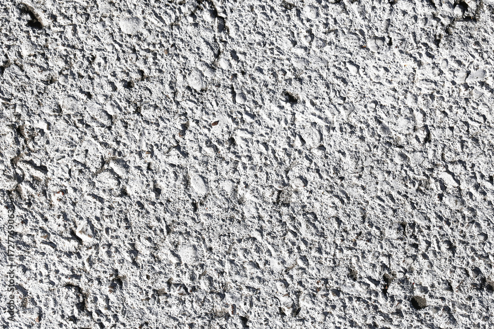 Fototapeta premium Rough gray plaster texture background. Cement wall surface with uneven grain structure. Grunge pattern of construction material for building industry. Abstract solid wall detail.