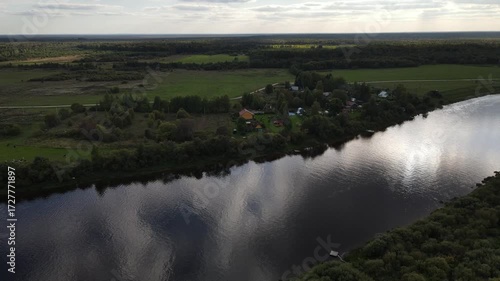 a small settlement on the riverbank in summer among greenery and trees