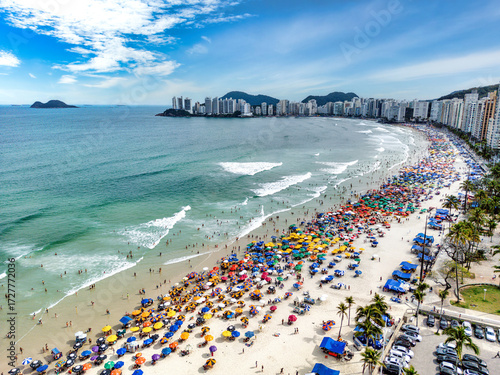 Vista aérea de dia ensolarado com muitos turistas na Praia de Pitangueiras no litoral paulista, Guarujá. 