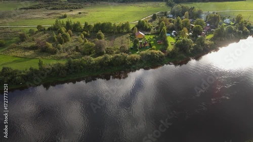 a small settlement on the riverbank in summer among greenery and trees