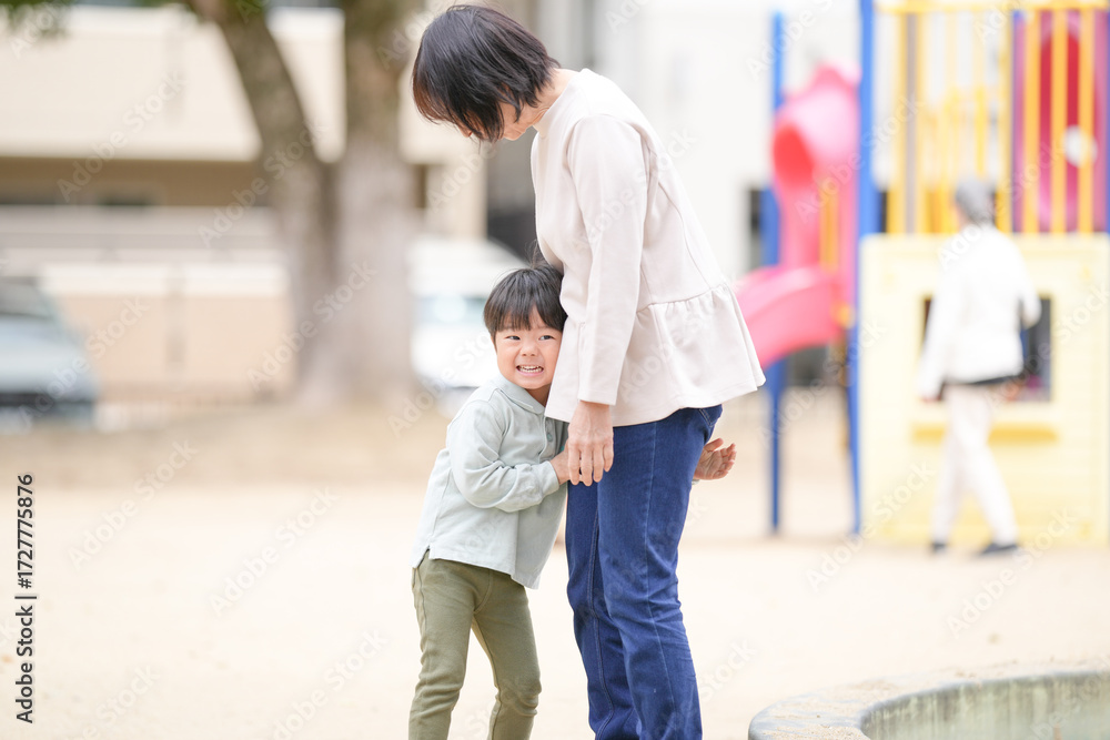 Fototapeta premium A woman and a child are standing next to each other in a park. The woman is holding the child's hand