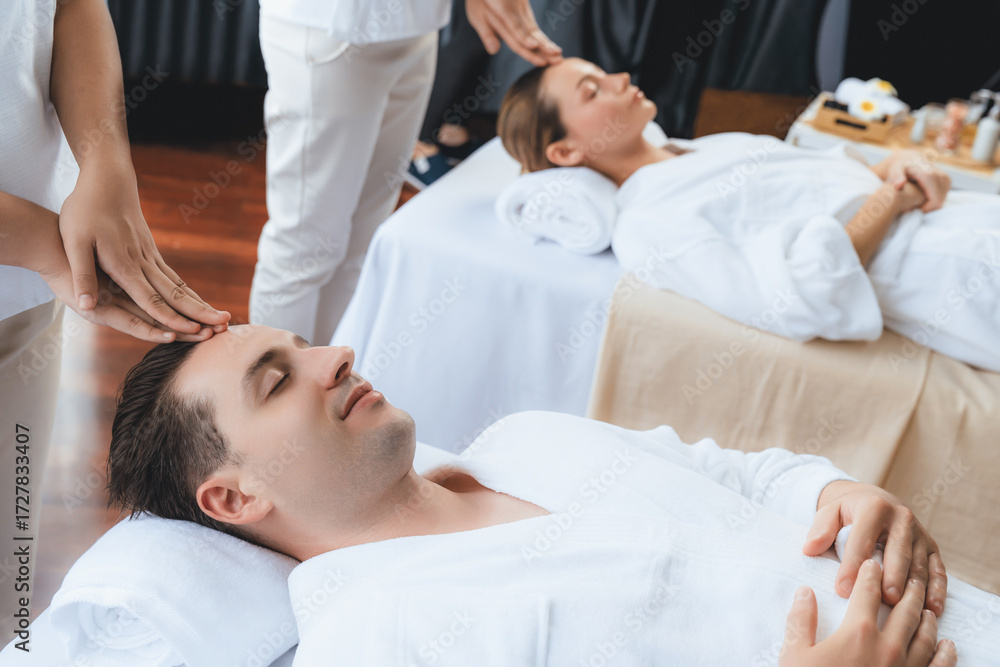 Obraz premium Caucasian couple enjoying relaxing anti-stress head massage and pampering facial beauty skin recreation leisure in dayspa modern light ambient at luxury resort or hotel spa salon. Quiescent