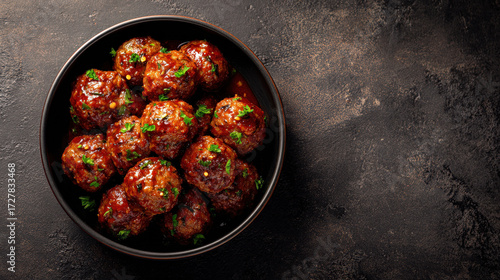 Delicious meatballs in a bowl, ready to be enjoyed. The meatballs are covered in a rich sauce and garnished with fresh herbs. This culinary delight is perfect for a satisfying meal.