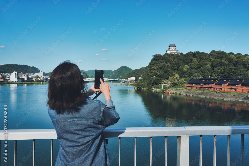 Fototapeta premium 犬山城をスマホで撮影する女性