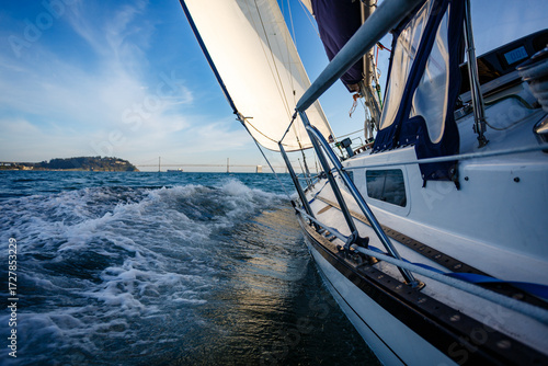 Photography Sailboat sailing on the water with a bridge in background