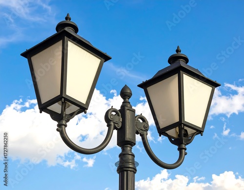 Two vintage-style black street lamps against a partly cloudy blue sky