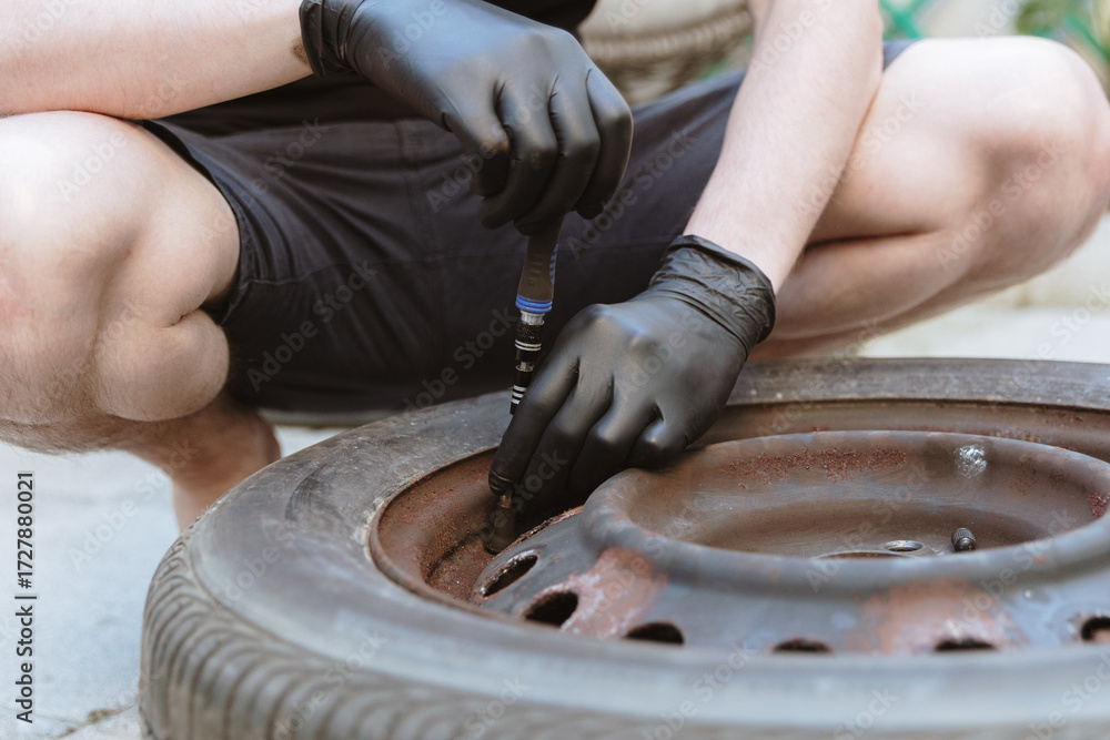Fototapeta premium A young man disassembles old car tires.