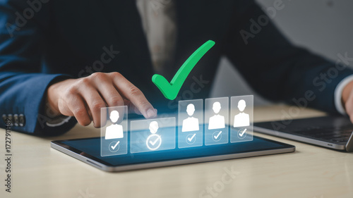 A businessman is using a tablet to select the best candidate for a job, with a green check mark indicating the selected candidate