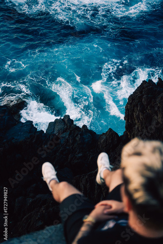 man sitting on the rock with waves underneath him