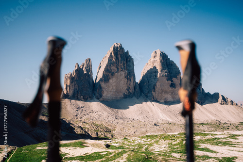 three peaks on sunny day with hiking sticks in the front