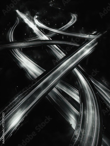 Aerial night view of multiple intersecting highways with light trails creating dynamic patterns in monochrome