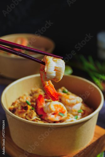 Pad Thai stir-fried with shrimp, eggs, peanuts and lime, served in paper.