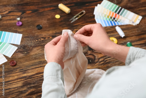 Woman sewing button on shir...
