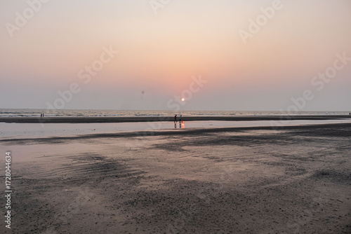 Peaceful Cox's Bazar beach view with parasailing in the distance during a calm evening, Bangladesh.