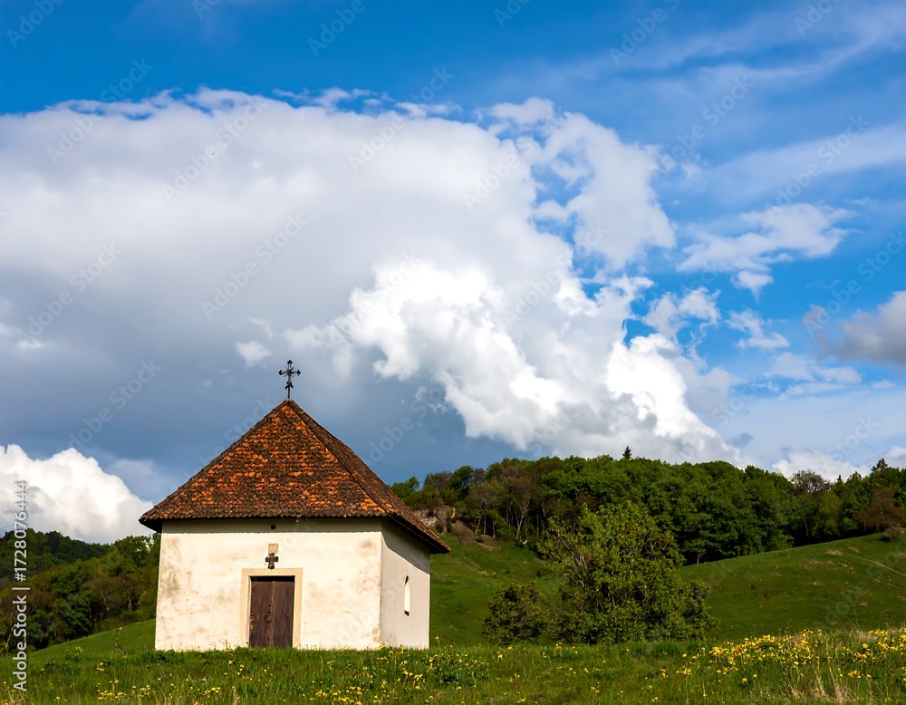 Fototapeta premium Small chapel on a grassy hill under a partly cloudy sky
