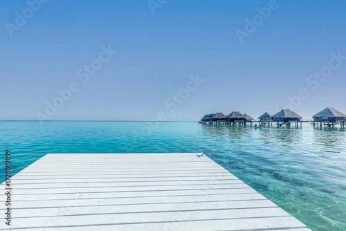 Wallpaper Mural Ponton en bois qui mène au lagon turquoise avec des bungalows sur pilotis au loin en Polynésie Torontodigital.ca
