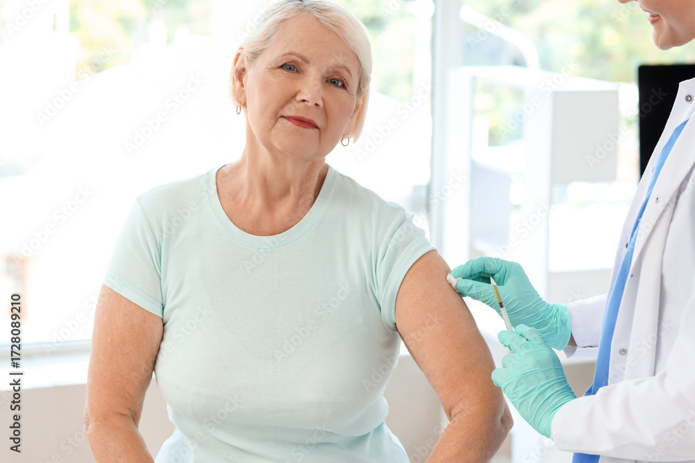 Fototapeta premium Female doctor vaccinating senior woman in clinic