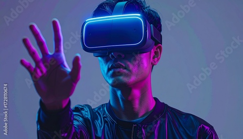 Portrait of an Asian man wearing a sleek virtual reality headset. Captured in a professional gray studio setting. Subtle neon blue and purple reflections highlight the contours of the device and face.