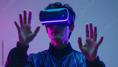 Portrait of an Asian man wearing a sleek virtual reality headset. Captured in a professional gray studio setting. Subtle neon blue and purple reflections highlight the contours of the device and face.