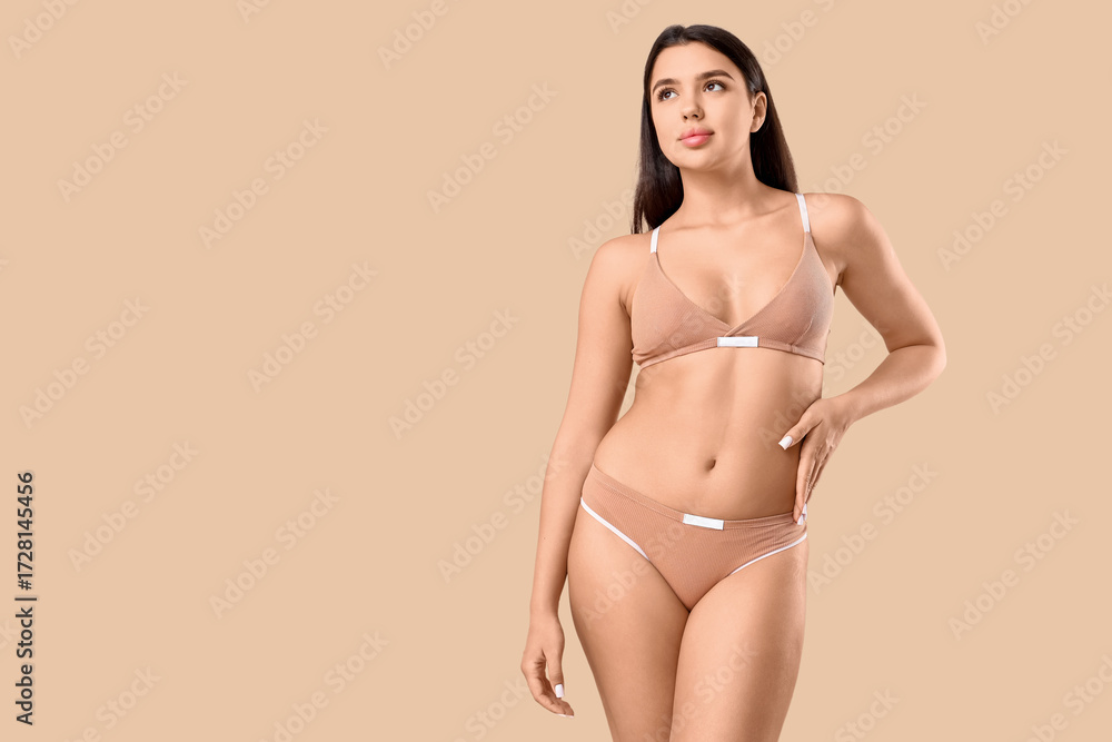Naklejka premium Beautiful young woman in cotton underwear on beige background