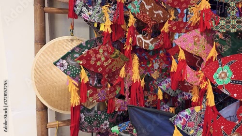 A vibrant collection of colorful batik wau placed against a bamboo frame for sale at the retail.