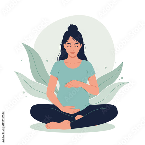 A pregnant woman is sitting in a peaceful meditation pose with her hands on her belly surrounded by soft green leaves.