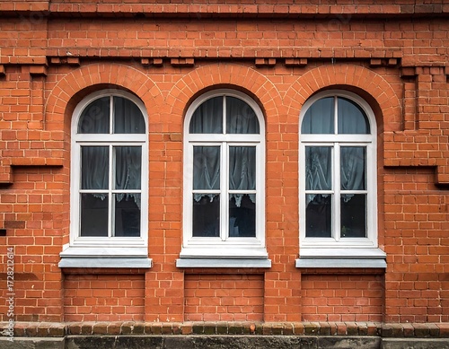 Three arched windows in a red brick wall