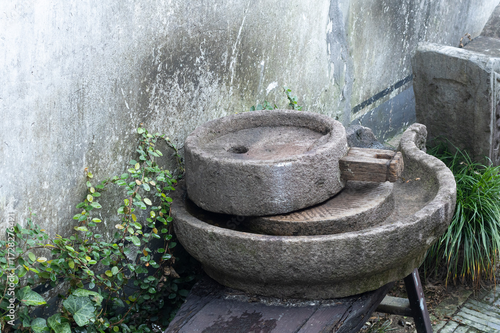 Fototapeta premium Ancient Stone Mill Wheel in a Lush Garden Setting