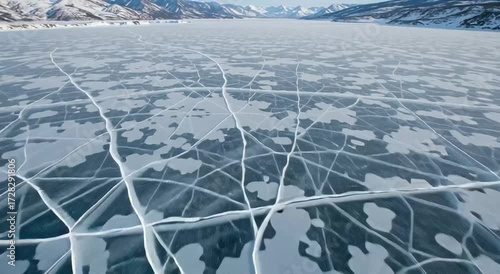 Frozen lake surface with cracks and patterns in winter landscape  